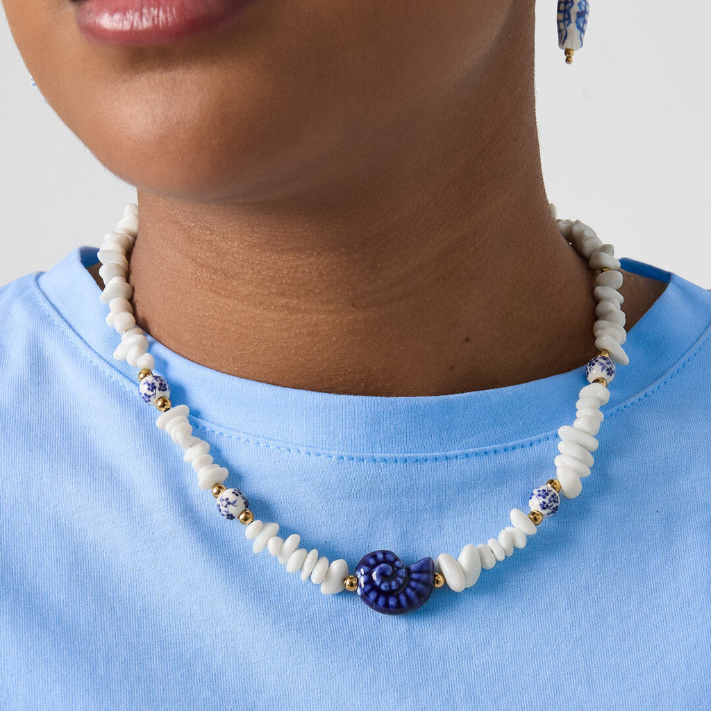 Collier composé de perles de pierre, de perles blanches ornées de fleurs bleues et d'un coquillage décoratif.